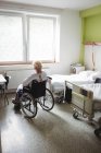 Mujer mayor sentada en silla de ruedas en el hospital - foto de stock
