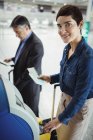 Бизнесвумен с помощью автомата самообслуживания при регистрации в аэропорту — стоковое фото