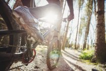 Low section of mountain biker riding in forest — Stock Photo