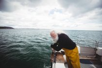 Старший рыбак смотрит в море с рыболовного судна — стоковое фото