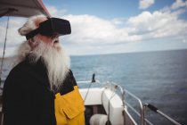 Рыбак с помощью гарнитуры виртуальной реальности на рыбацкой лодке — стоковое фото