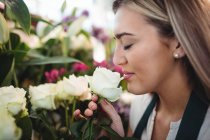 Крупный план женщины-флориста, нюхающей цветок в своем цветочном магазине — стоковое фото