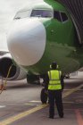 Вид сзади на наземного работника аэропорта, направляющего самолет на взлетно-посадочную полосу — стоковое фото
