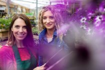 Женщины-флористы держат планшет в садовом центре — стоковое фото