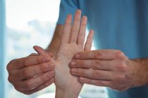 Geschnittenes Bild eines männlichen Physiotherapeuten, der einer Patientin in der Klinik die Hand massiert — Stockfoto