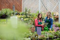Duas floristas femininas usando tablet digital no centro de jardim — Fotografia de Stock