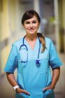 Porträt einer Krankenschwester, die mit den Händen in der Tasche auf dem Krankenhausflur steht — Stockfoto
