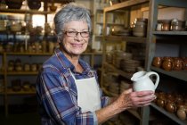 Portrait of female potter holding jug in pottery workshop — Stock Photo