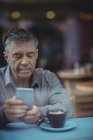 Hombre sosteniendo periódico y tomando café en la cafetería - foto de stock