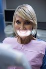 Paziente con sorriso bianco seduto sulla sedia del dentista in clinica — Foto stock