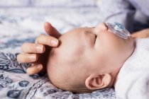 Primer plano del bebé durmiendo con maniquí en la boca en la cama en casa - foto de stock