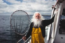 Portrait of fisherman holding fishing net on boat — Stock Photo