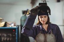 Portrait of female welder standing in workshop — Stock Photo