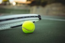 Close-up of tennis racket and ball in green court — Stock Photo