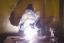 Schweißerin bearbeitet Metallstück in Werkstatt — Stockfoto
