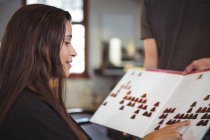 Smiling woman selecting hair color with stylist at hair salon — Stock Photo