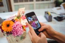 Mãos de florista feminino tirando fotografia de flores na loja de flores — Fotografia de Stock
