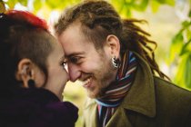 Close-up de casal hipster romântico olhando um para o outro, enquanto em pé no parque — Fotografia de Stock