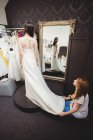 Mujer probándose el vestido de novia en el estudio con la ayuda del diseñador creativo - foto de stock
