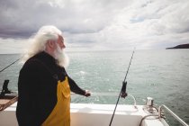 Vista laterale del pescatore premuroso in piedi sulla barca da pesca — Foto stock