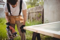 Carpenter working with circular saw outside house — Stock Photo