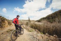 Radfahrer fährt Fahrrad auf Feldweg am Berg — Stockfoto