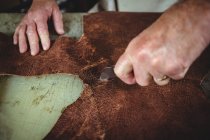 Hände des Schuhmachers, der in der Werkstatt ein Stück Leder schneidet — Stockfoto