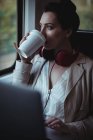 Junge Frau trinkt Kaffee durch Fenster im Zug — Stockfoto