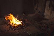 Hand des Schmieds erhitzt ein Metallstück in der Werkstatt — Stockfoto