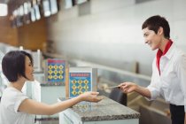 Airline check-in attendant handing passport to passenger at airport check-in counter — Stock Photo