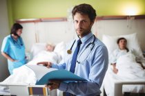 Portrait of doctor checking report in hospital — Stock Photo