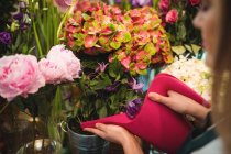Primo piano di fiorista femminile versando acqua in vaso di fiori al suo negozio di fiori — Foto stock