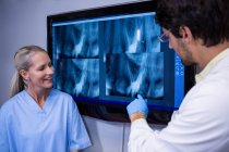 Dentista e assistente dentário discutindo um raio-x no monitor na clínica odontológica — Fotografia de Stock