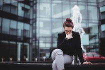 Напряженная деловая женщина сидит напротив офисного здания — стоковое фото