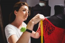 Diseñador creativo vestido de medición en maniquí con cinta métrica en el estudio - foto de stock