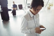 Passeggero asiatico femminile che utilizza il telefono cellulare nel terminal dell'aeroporto — Foto stock