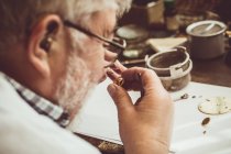 Rückansicht eines Uhrmachers, der in der Werkstatt eine Uhr repariert — Stockfoto