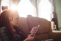 Молодая женщина хипстер с помощью цифрового планшета, сидя дома на диване — стоковое фото