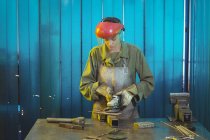 Женщина-сварщик с помощью циркулярной пилы в мастерской — стоковое фото