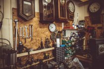 Oficina de horólogos antigos com ferramentas de reparo de relógio, equipamentos e relógios na parede — Fotografia de Stock