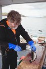 Grey hair Fisherman filleting fish in boat — Stock Photo