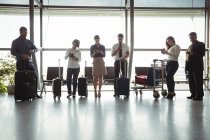 Business people using mobile phones in waiting area at airport terminal — Stock Photo