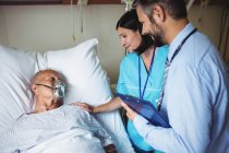 Медсестра втішає старшого пацієнта з лікарем у лікарні — стокове фото