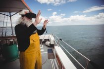 Рибалка використовує гарнітуру віртуальної реальності на рибальському човні — стокове фото