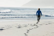 Серфер, гуляющий по пляжу в солнечный день — стоковое фото