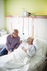 Старший мужчина утешает пожилую женщину в больнице — стоковое фото