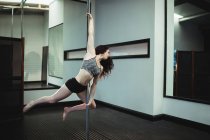 Hermosa bailarina polaca practicando pole dance en gimnasio - foto de stock