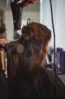 Задній вид офіціантка, отримуючи її волосся сушать фен для волосся в перукарні — стокове фото