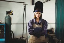 Porträt einer Schweißerin, die mit verschränkten Armen in der Werkstatt steht — Stockfoto