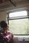 Продумана жінка дивиться крізь вікно, маючи каву в поїзді — стокове фото